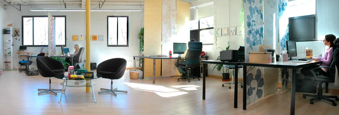 Bartlett Interactive's office, a bright open studio with desks by tall windows and two black lounge chairs around a glass table